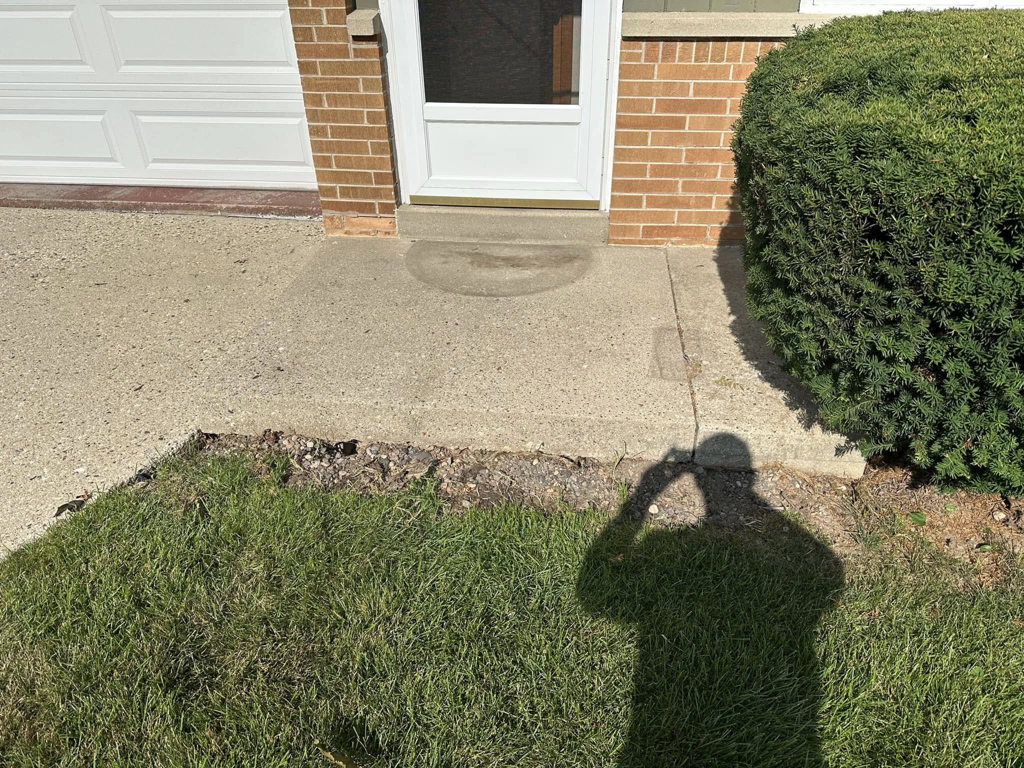 Newly poured concrete apron and sidewalk at garage entrance with smooth finish and clean edge
